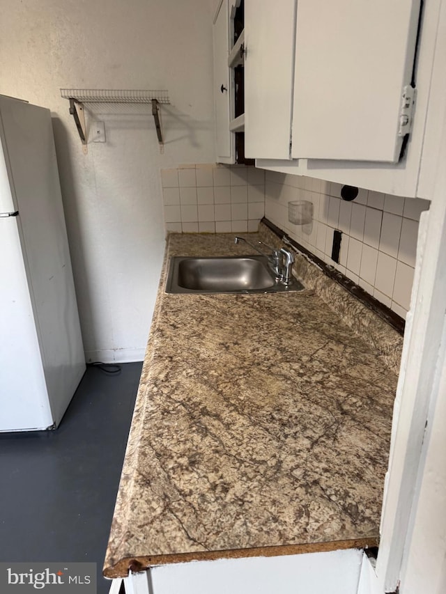 kitchen with tasteful backsplash, white cabinetry, sink, and white fridge