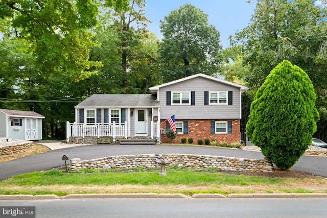 split level home with covered porch and a storage unit