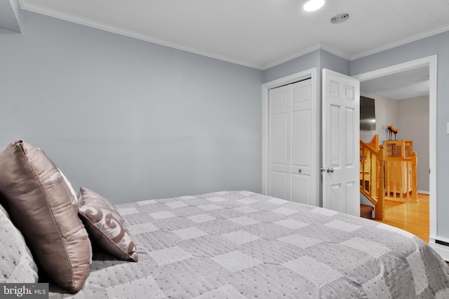 bedroom with hardwood / wood-style floors, crown molding, and a closet