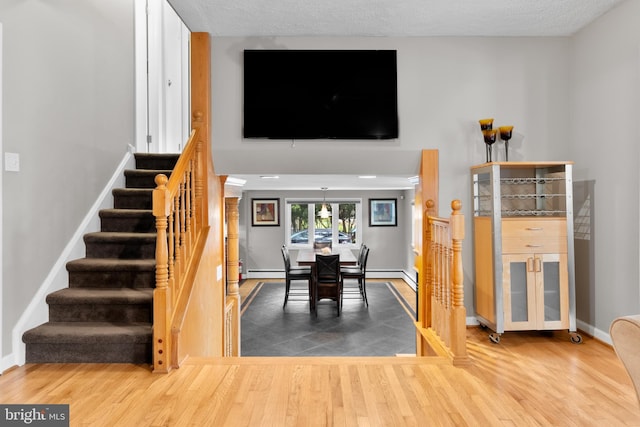 staircase featuring hardwood / wood-style floors, a baseboard radiator, and a textured ceiling