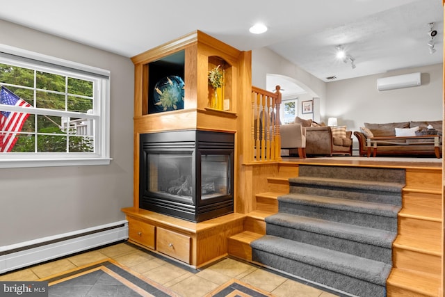 interior space with a multi sided fireplace, an AC wall unit, baseboard heating, and lofted ceiling