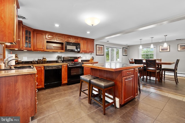 kitchen with a center island, black appliances, a kitchen breakfast bar, sink, and hanging light fixtures