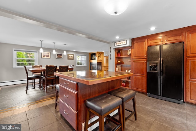 kitchen with a center island, hanging light fixtures, a baseboard radiator, a breakfast bar area, and black fridge with ice dispenser