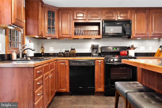 kitchen with sink, dark tile patterned floors, and black appliances