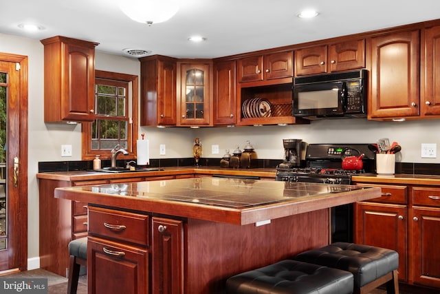 kitchen featuring a kitchen bar, sink, a center island, and black appliances