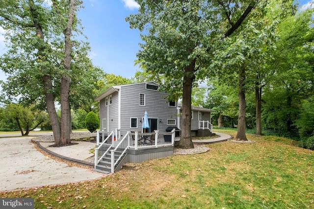 back of property featuring a yard and a wooden deck