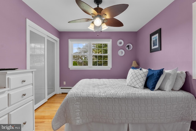 bedroom featuring light wood-type flooring, ceiling fan, and a baseboard heating unit