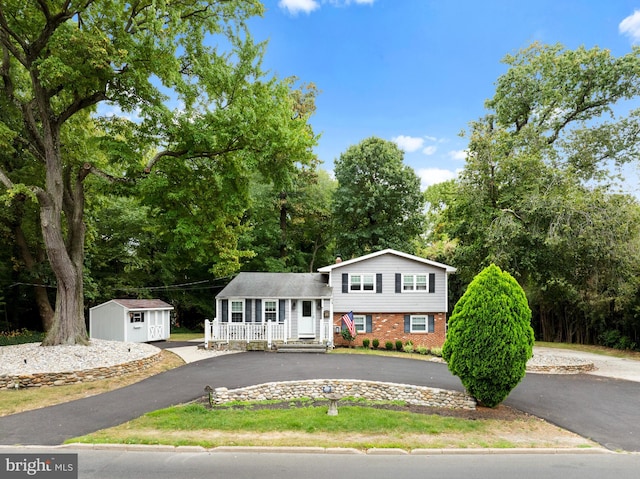 tri-level home featuring covered porch and a storage unit