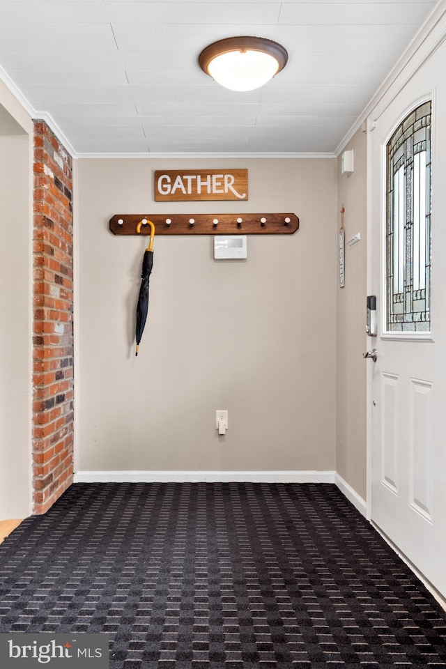 entrance foyer featuring dark colored carpet and ornamental molding