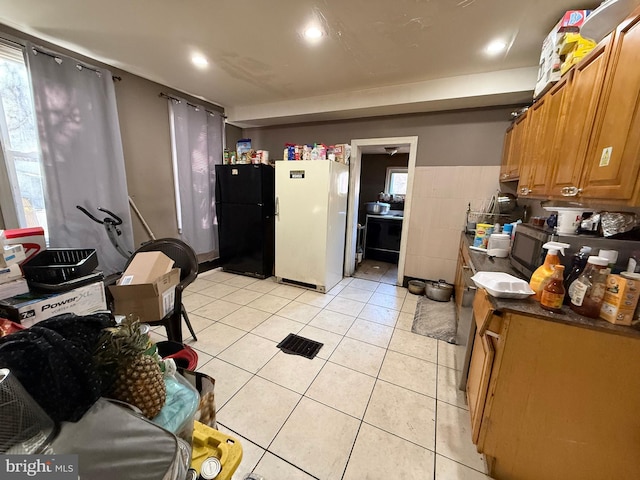 kitchen featuring black fridge, light tile patterned floors, and white refrigerator