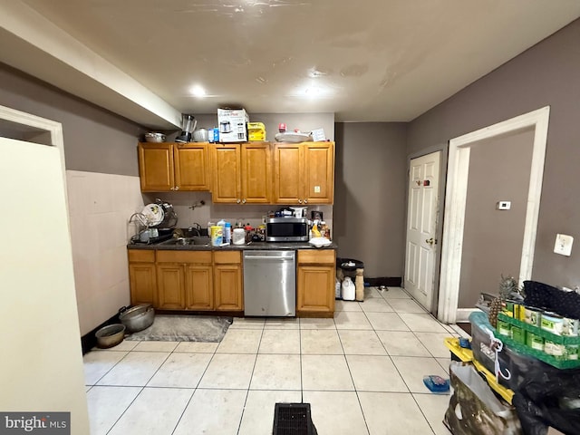 kitchen with sink, light tile patterned floors, stainless steel appliances, and tile walls