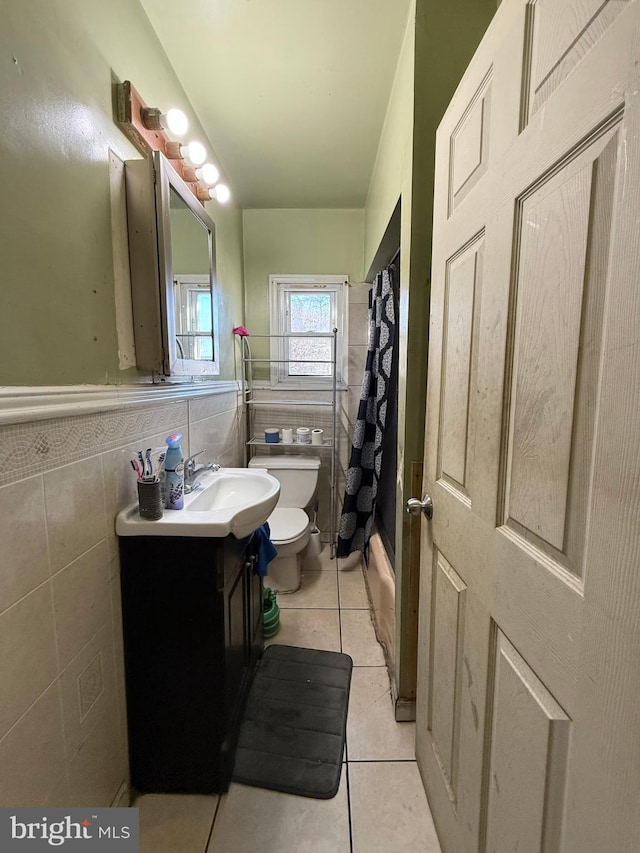 full bathroom featuring tile patterned floors, vanity, shower / tub combo with curtain, tile walls, and toilet