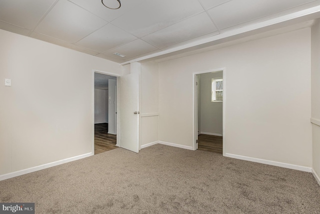 carpeted empty room with a paneled ceiling