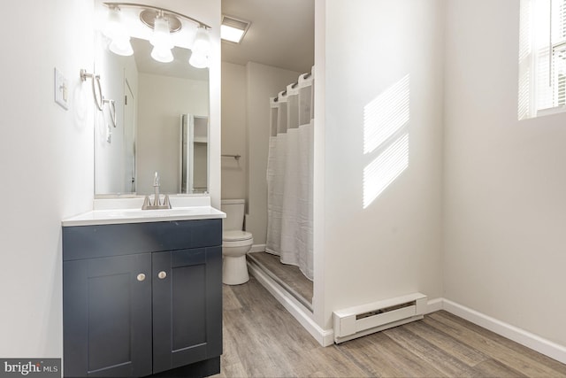 bathroom featuring baseboard heating, vanity, wood-type flooring, and toilet