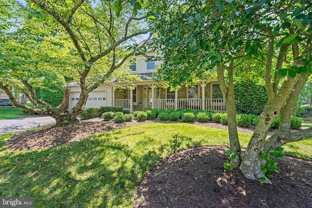 view of property hidden behind natural elements with a porch, a garage, and a front lawn