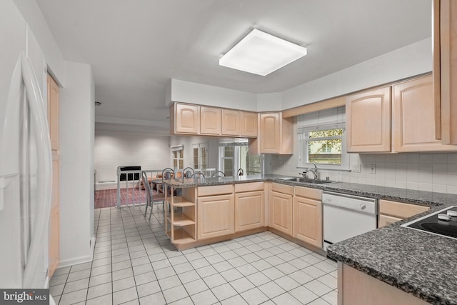 kitchen with light brown cabinets, sink, white appliances, and kitchen peninsula