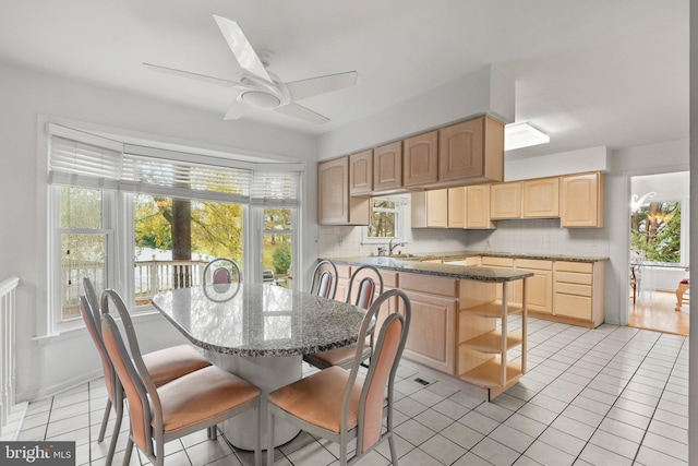 kitchen featuring a center island, light brown cabinets, decorative backsplash, ceiling fan, and light tile patterned flooring