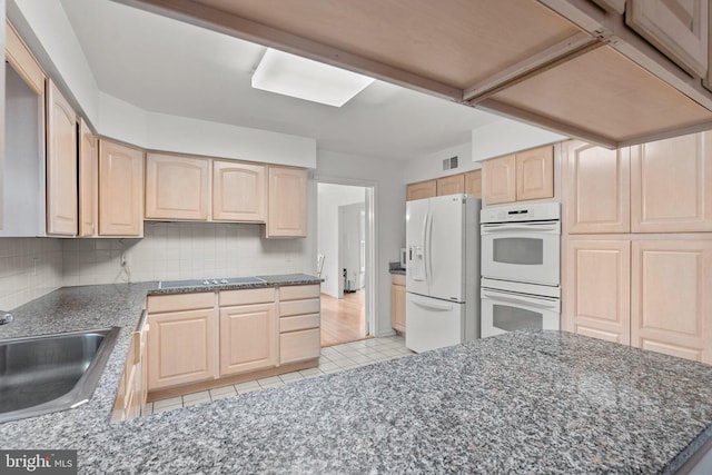 kitchen with backsplash, white appliances, sink, and light brown cabinetry