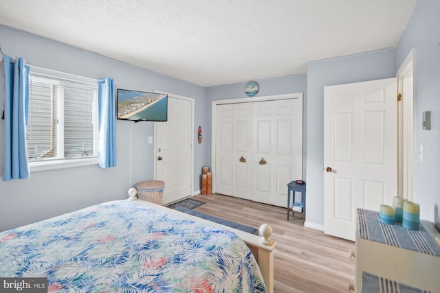 bedroom with a textured ceiling, light hardwood / wood-style floors, and a closet