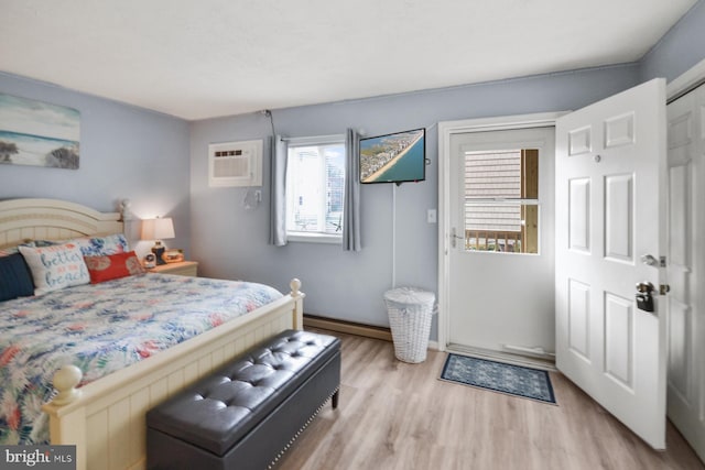 bedroom with a wall unit AC and light hardwood / wood-style flooring