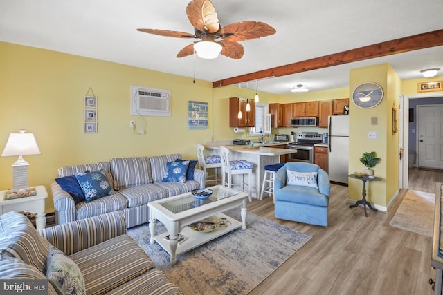 living room with ceiling fan, sink, a wall mounted air conditioner, and light wood-type flooring