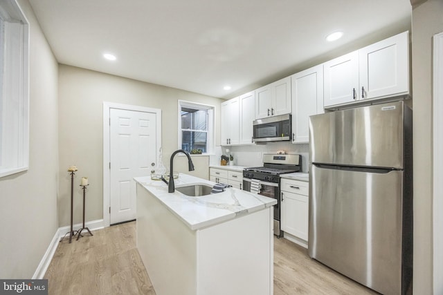 kitchen with white cabinets, sink, appliances with stainless steel finishes, and an island with sink