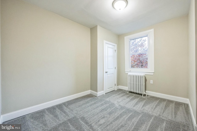 spare room featuring carpet and radiator