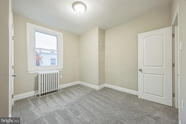 spare room with radiator heating unit and light colored carpet