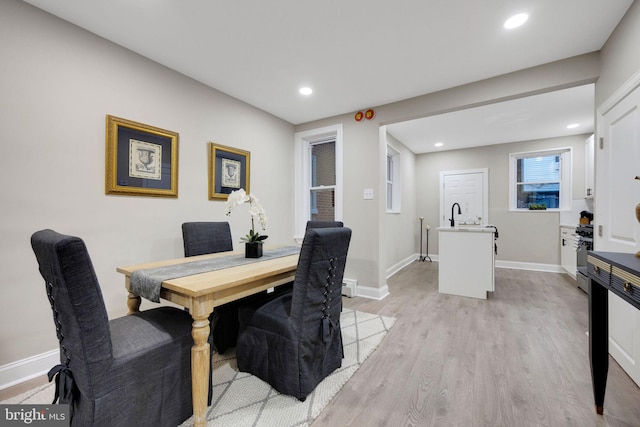 dining room with baseboard heating, sink, and light wood-type flooring