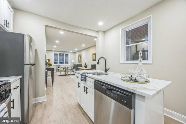 kitchen featuring sink, white cabinets, stainless steel appliances, and light wood-type flooring