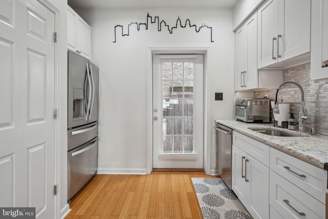 kitchen featuring stainless steel appliances, white cabinetry, light hardwood / wood-style floors, and sink