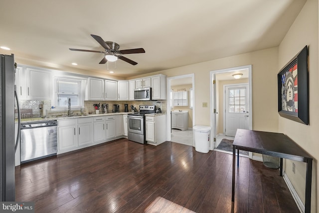 kitchen featuring decorative backsplash, appliances with stainless steel finishes, dark hardwood / wood-style flooring, sink, and white cabinetry