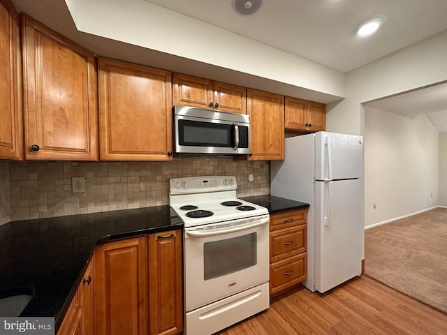 kitchen with light wood-type flooring, white appliances, and backsplash