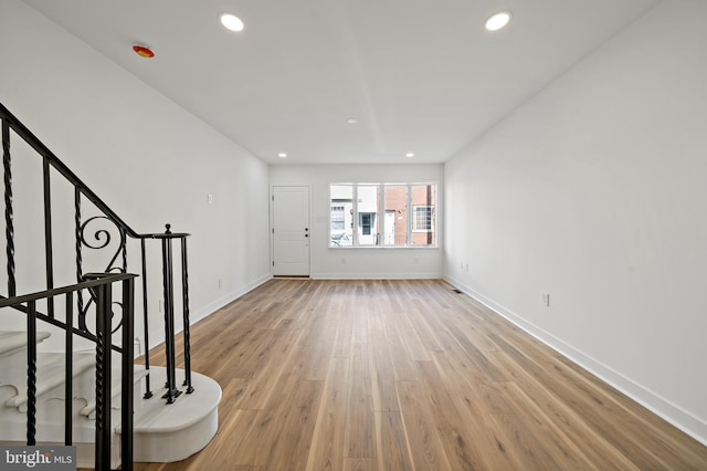 unfurnished living room with stairs, recessed lighting, light wood-type flooring, and baseboards