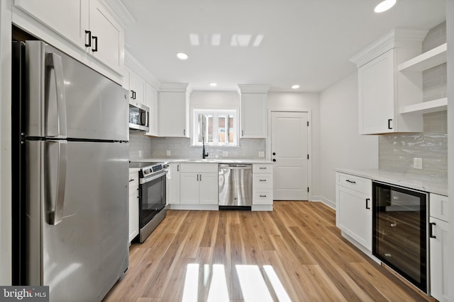 kitchen featuring white cabinetry, beverage cooler, tasteful backsplash, light hardwood / wood-style floors, and appliances with stainless steel finishes