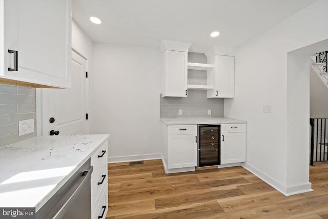 kitchen with backsplash, white cabinetry, light hardwood / wood-style flooring, and beverage cooler