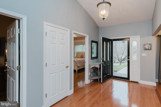 entrance foyer with wood-type flooring and vaulted ceiling