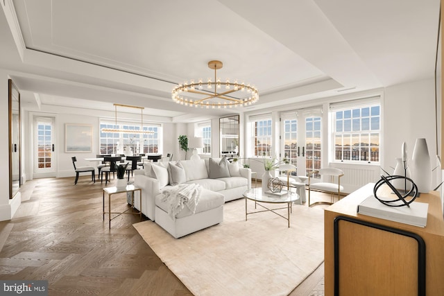 living room with a notable chandelier, parquet flooring, french doors, and a tray ceiling