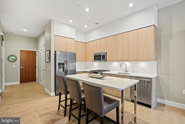 kitchen featuring a breakfast bar, sink, light wood-type flooring, and appliances with stainless steel finishes