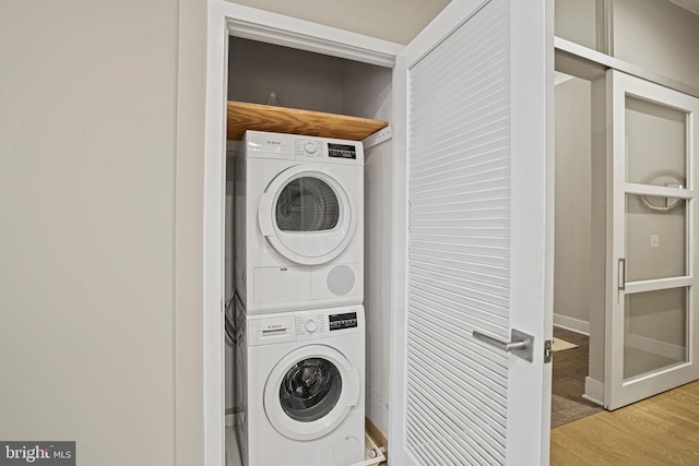 laundry room featuring stacked washing maching and dryer and light wood-type flooring