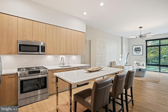 kitchen featuring decorative backsplash, light wood-type flooring, stainless steel appliances, sink, and light brown cabinets