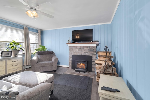 living room featuring ceiling fan, dark hardwood / wood-style flooring, ornamental molding, and a wood stove