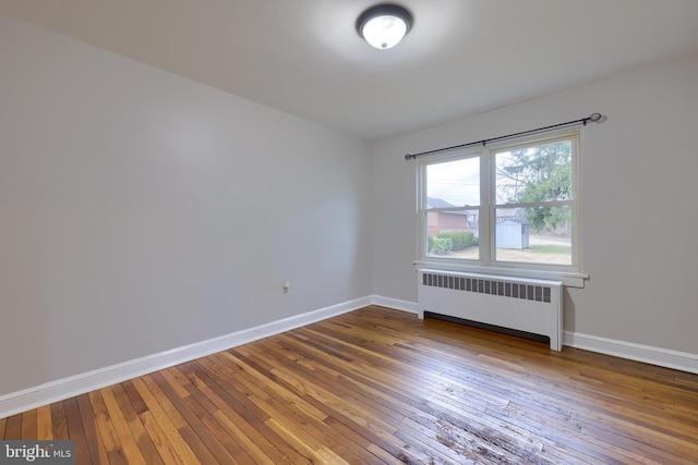 unfurnished room featuring radiator and hardwood / wood-style floors