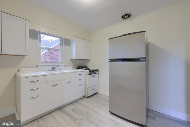 kitchen with stainless steel refrigerator, sink, white range oven, white cabinets, and light wood-type flooring