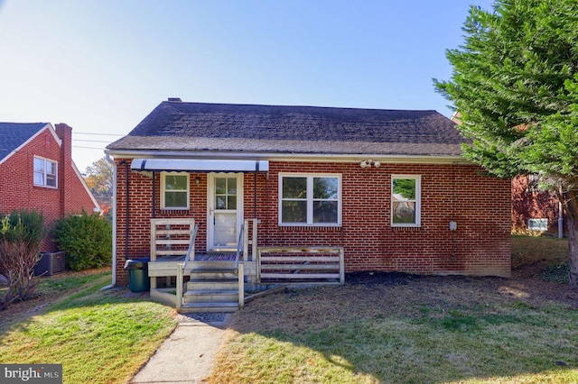 bungalow-style home with central air condition unit and a front yard