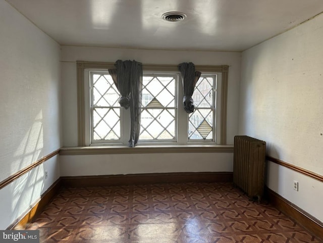 unfurnished room with radiator heating unit and light parquet flooring