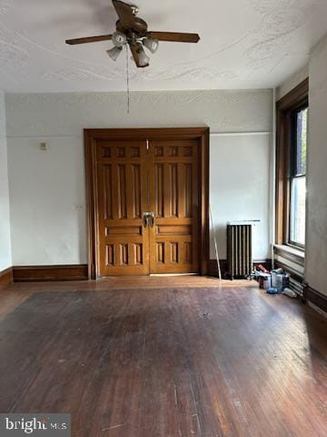 empty room featuring ceiling fan, radiator heating unit, and hardwood / wood-style floors