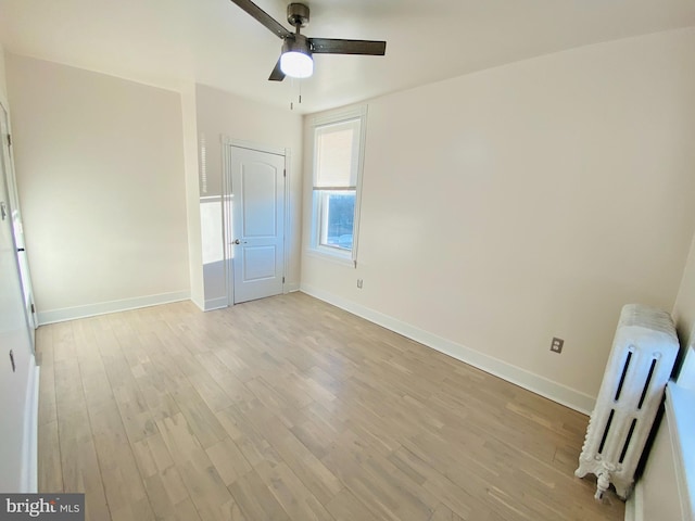 unfurnished bedroom with ceiling fan, radiator heating unit, and light wood-type flooring