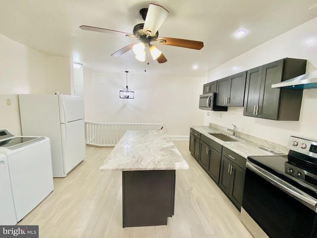 kitchen with stainless steel appliances, sink, washer and dryer, light hardwood / wood-style flooring, and a kitchen island