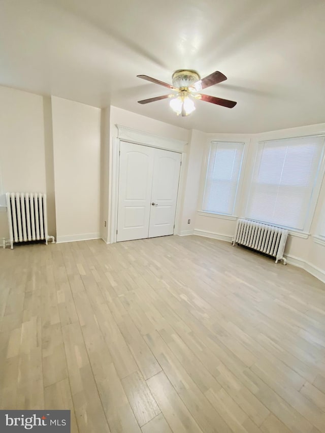 bonus room with ceiling fan, radiator heating unit, and light hardwood / wood-style flooring